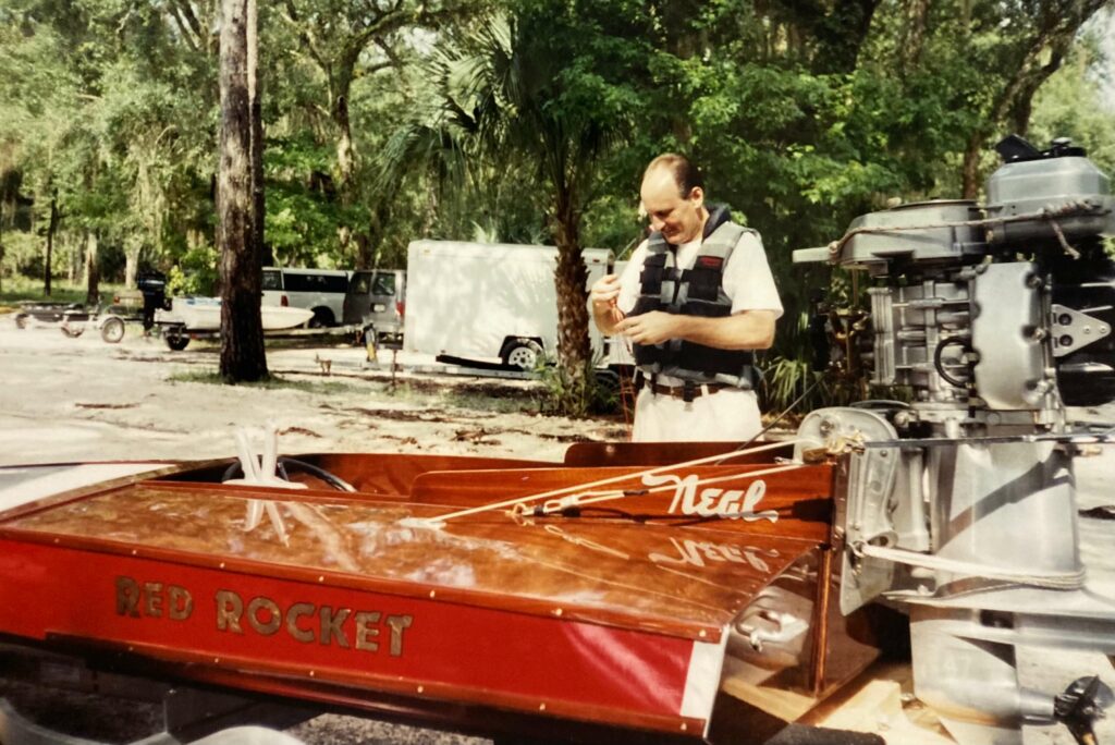 Ron Corder Customs A man standing next to a red rocket boat.