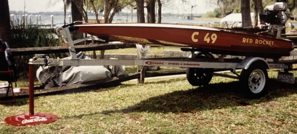 Ron Corner Customs red boat on a hitch sitting on the grass