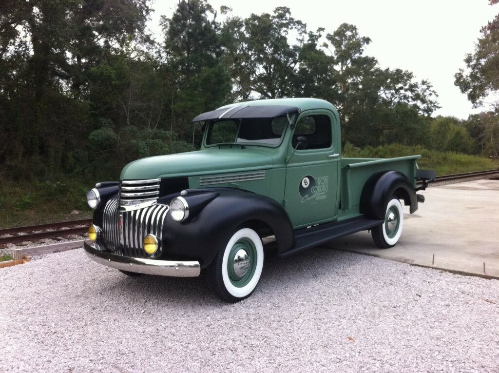 Ron Corder Customs An old green pickup truck is parked on the side of the road.