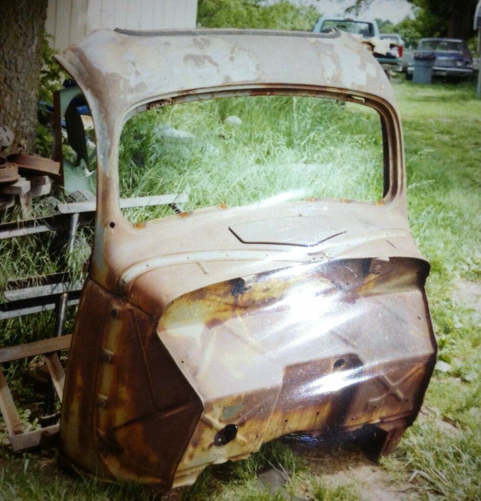 Ron Corder Customs A rusted old car sitting in the grass.